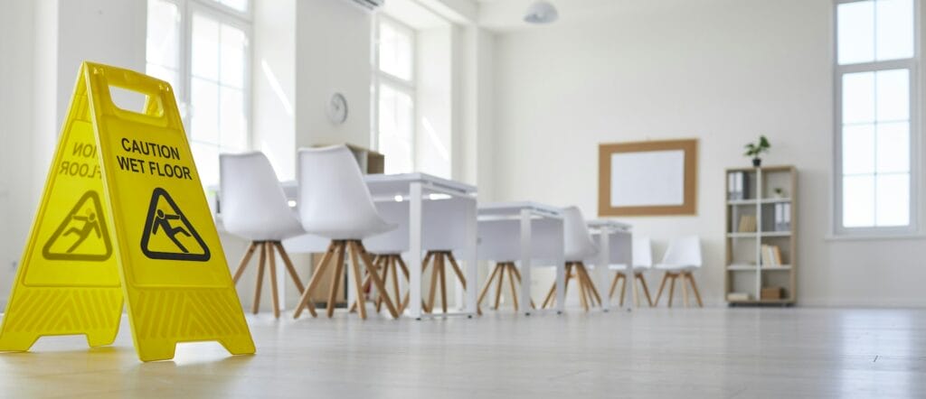 School classroom where cleaning service worker placed sign which reads Caution Wet Floor